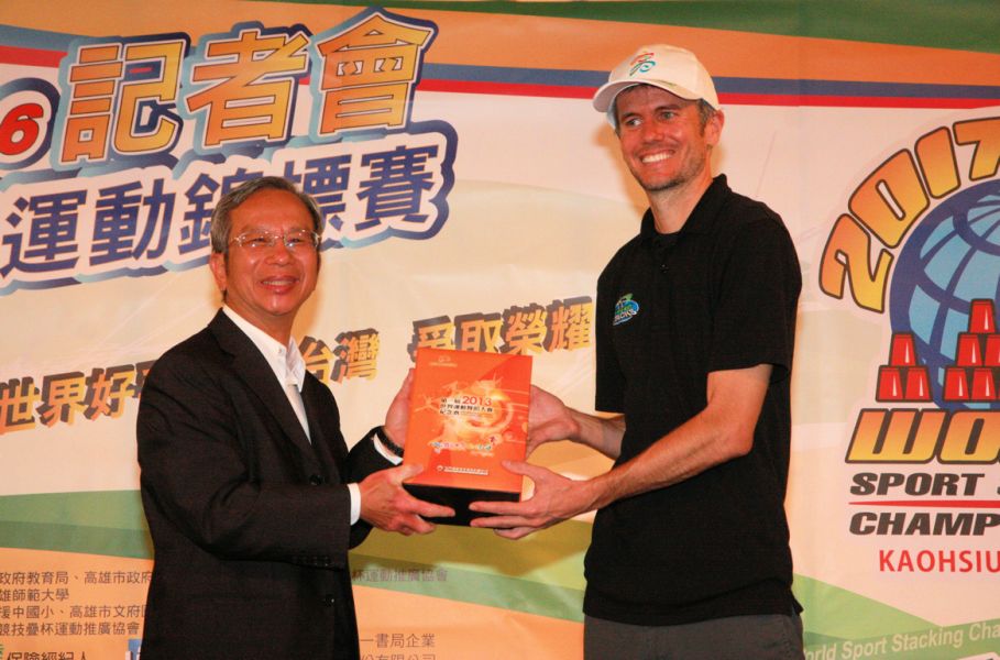 高雄市政府副秘書長林英斌（左）致贈世界競技疊杯總會的賽事經理Chad紀念酒。高雄市體育處提供