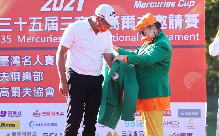 翁董事長夫人（右）為王偉祥穿上冠軍綠夾克。大會提供