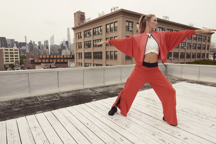 國際級超模Karlie Kloss身著adidas x Karlie Kloss 2021春季聯名系列橘紅短版寬袖外套，內搭同系列白色短袖T-shirt，打造隨興修身視覺效果。官方提供