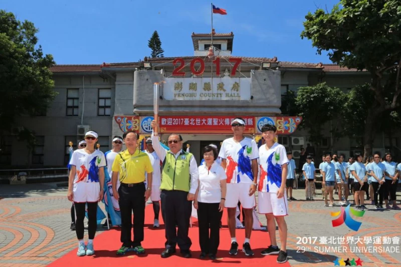 澎湖縣長陳光復自臺北世大運執行長蘇麗瓊手中接過聖火。台北世大運執委會提供