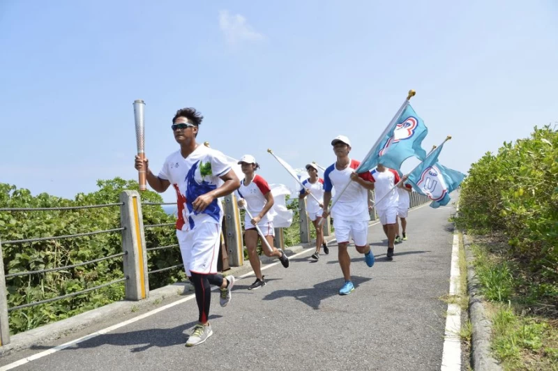 新北市火炬手成棒隊選手在濱海公路傳遞聖火。台北世大運執委會提供