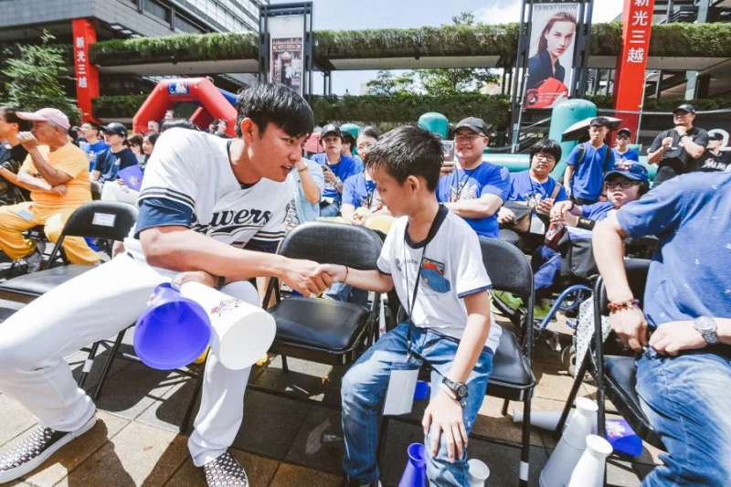 王維中連續三年擔任MLB棒球樂園活動大使,看到同樣連續三年參與的罕病病童吳兆峰開心握手。(大漢集團提供)