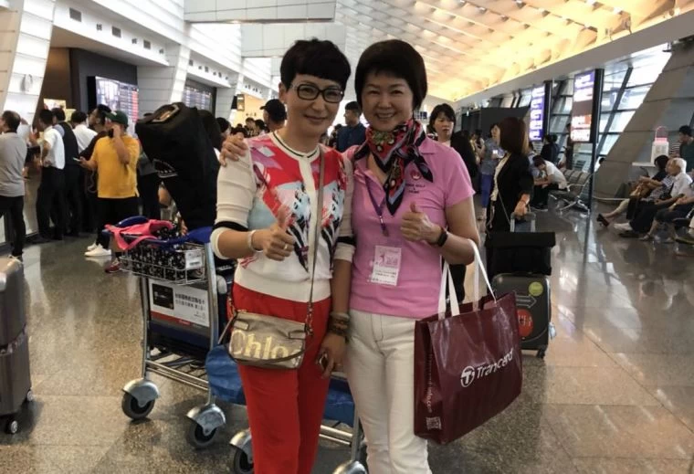 香港隊長張毅(左)與中華婦女會會長何美貞在機場相見歡。