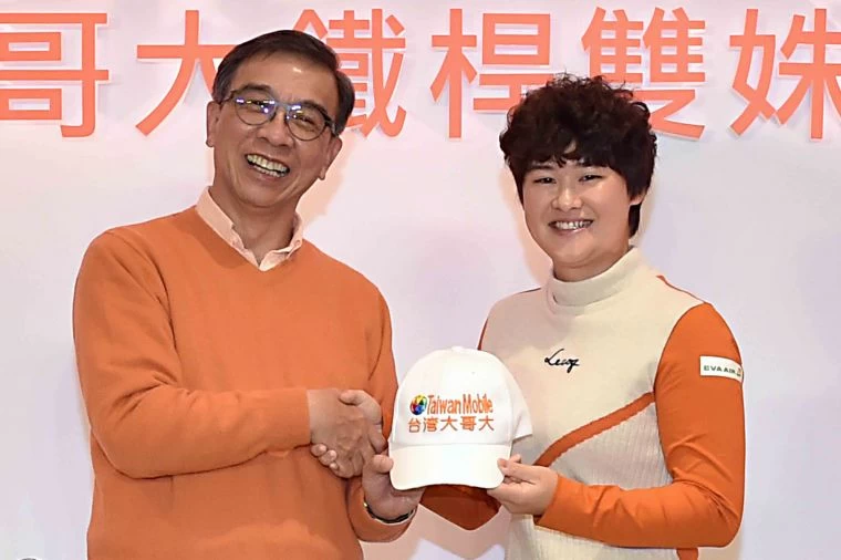 台灣大哥大總經理鄭俊卿(左),為李旻戴上繡有台灣大的球帽。