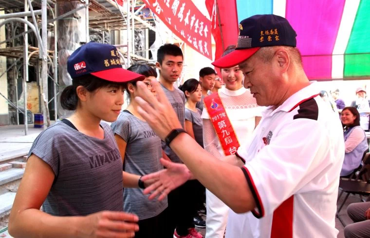 左營鳳邑城城隍廟主委李榮宗(右)為本市全運會鐵人三項選手贈經左營城隍爺親自加持護佑的運動帽。高雄市運動展局提供