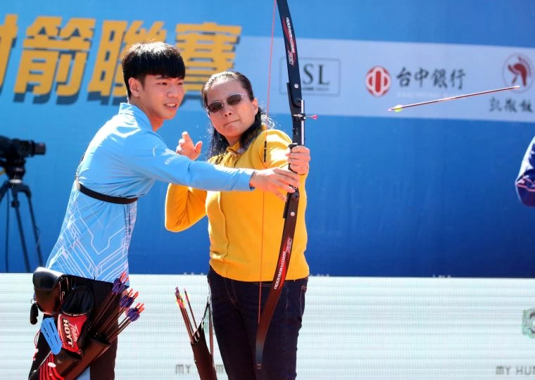 高佳萍的媽媽陸春美（右）在台南隊羅正偉指導下，成功射下達標禮。企業射箭聯盟／提供。