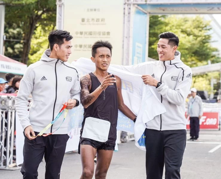 擔任2019臺北馬拉松活動大使的楊俊瀚(圖左)、陳傑(圖右),親自為馬拉松男子組國內冠軍蔣介文(圖中)遞上毛巾與完賽獎牌。臺北市政府提供