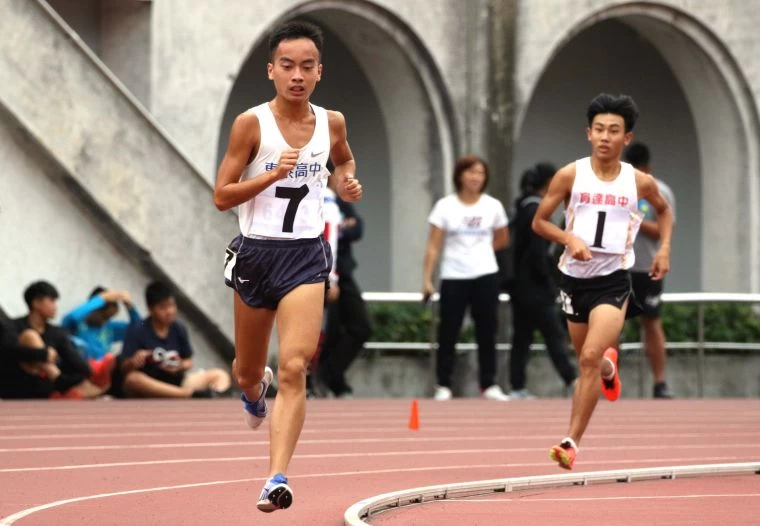 新竹縣東泰高中胡冠愷(前)在5000公尺決賽,最後一圈被桃園市育達高中黃柏憲(後)超車。林嘉欣/攝影。