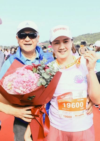 台新金控董事長吳東亮在終點獻上鮮花,熱情迎接成功征服21公里的夫人彭雪芬。路跑協會提供