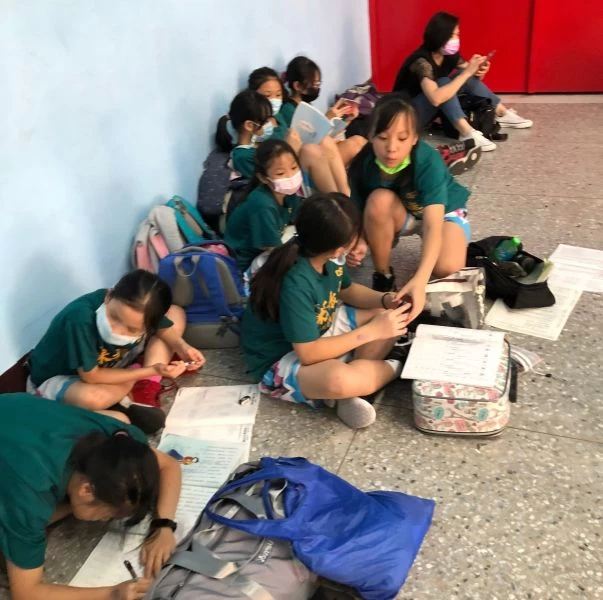 高峰球員集體席地而坐包包打開,課本、作業簿一攤,就地溫習功課。大會提供