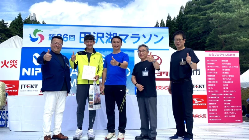 朱俊哲於2023第36屆田澤湖馬拉松20公里組獲得第六名的佳績,上台接受高雄市運發局長侯尊堯及仙北市長田口知明等人頒獎。高雄市府運發局提供