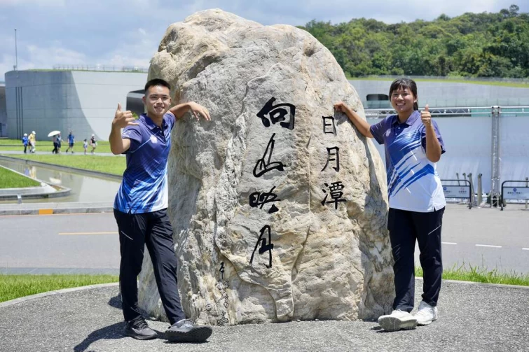 陳以錡(右)賽後當個觀光客與柯倫祐在景點前拍照留念。射箭協會提供